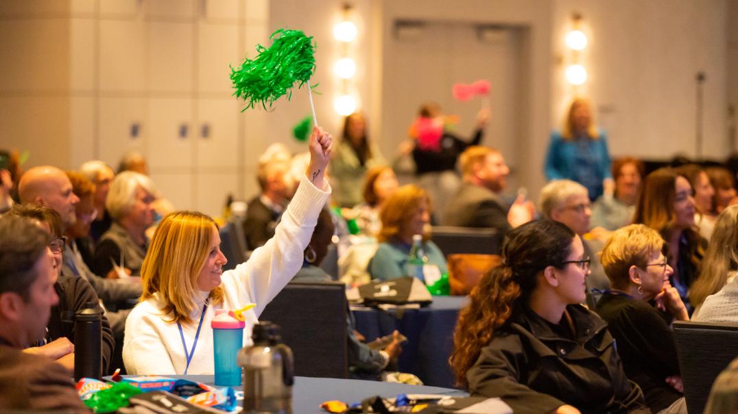 plenary with pom poms people at a conference raising pom poms