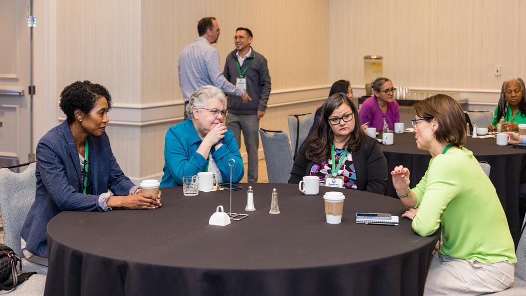 four women around a conference table talking