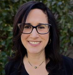 white woman with black hair and glasses wearing black shirt