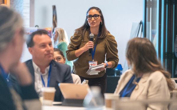 member holding mic speaking to table at 2022 Conf