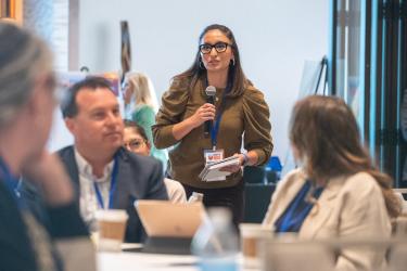 member holding mic speaking to table at 2022 Conf